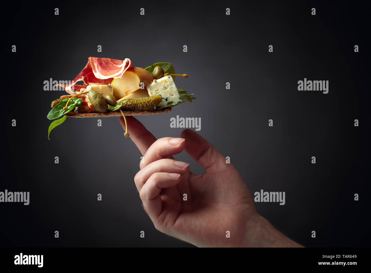 Sandwich mit Blauschimmelkäse, Prosciutto und Birnen garniert mit grünen, Kapern und cornichon. Kopieren spase, schwarzen Hintergrund. Stockfoto