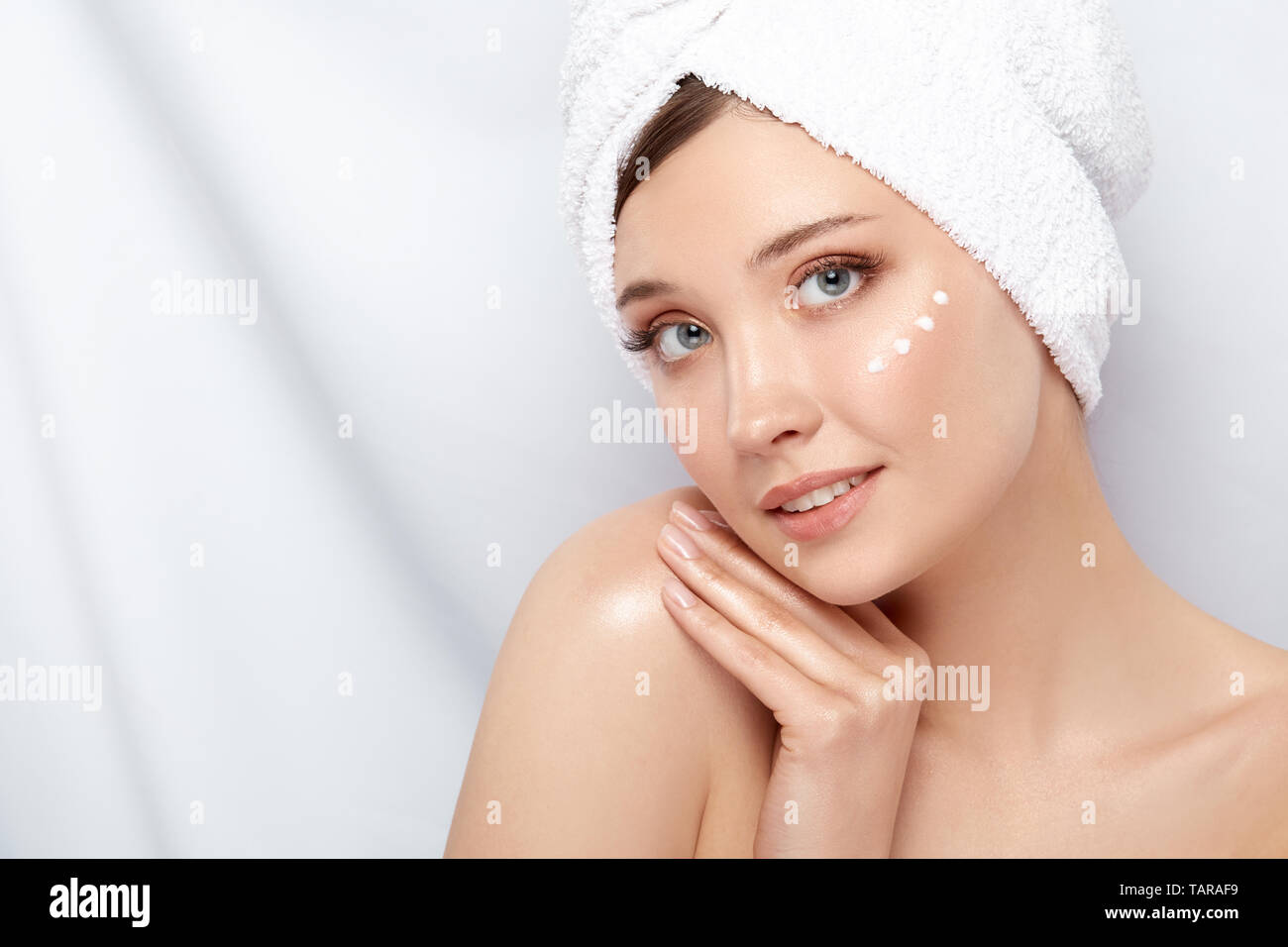 Attraktive Mädchen mit Handtuch auf dem Kopf die Schulter berühren und in Creme unter ihr Gesicht, Kopieren, close-up Stockfoto
