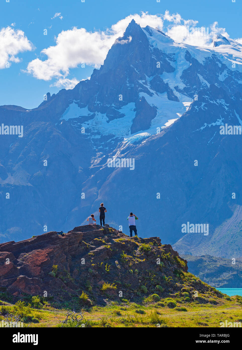 Vertikale Foto von drei Touristen mit Blick auf die Anden Gipfel des Paine Massivs und Pehoe See, Torres del Paine Nationalpark, Patagonien, Chile. Stockfoto