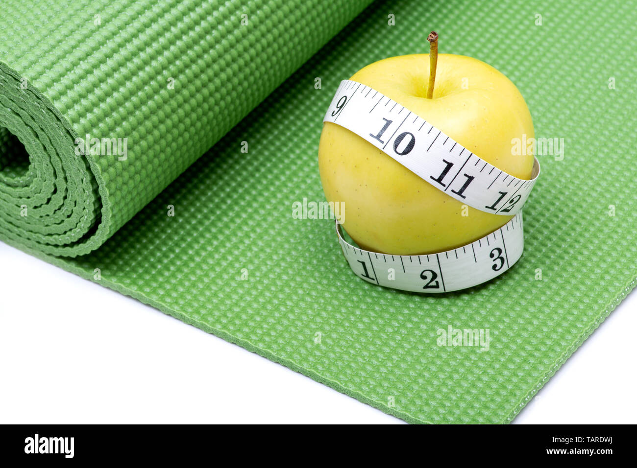 Gelber Apfel und weiches Vinyl Maßband auf Grün Yoga Matte. Stockfoto