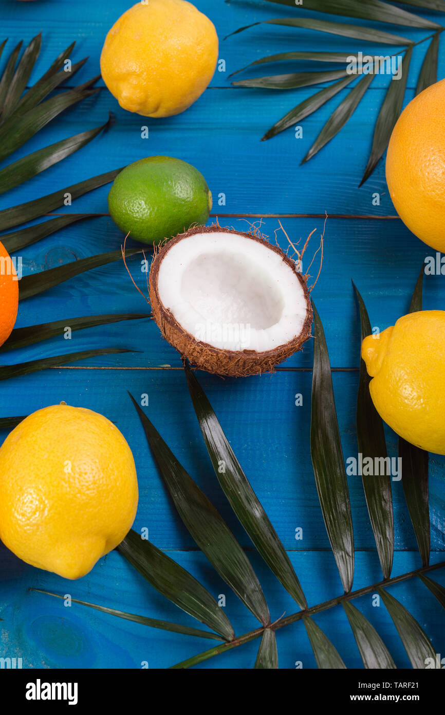 Verschiedene Früchte, grüne Blätter auf Blau Holztisch. Tropischer Sommer Hintergrund mit Stockfoto