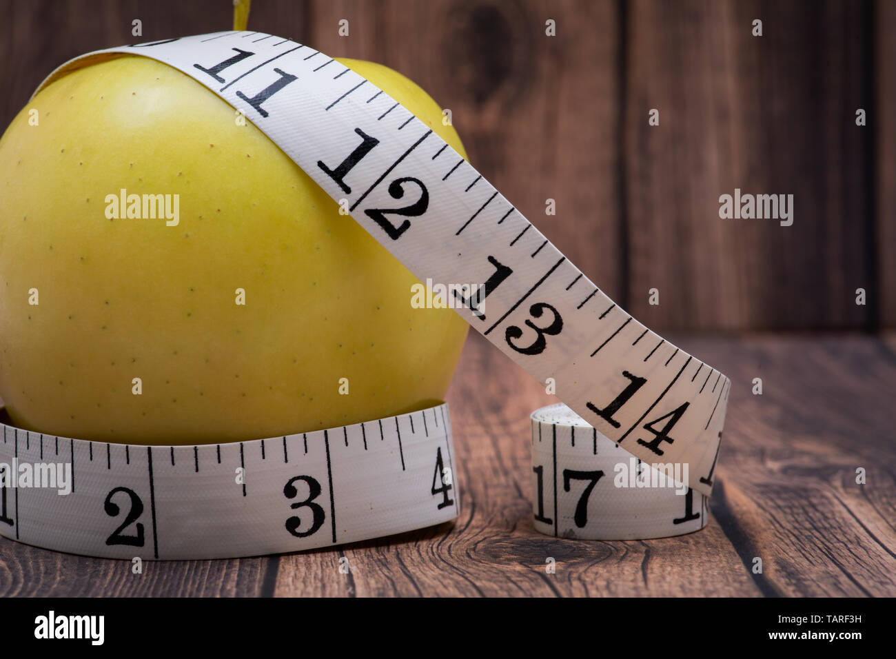Gelber Apfel und weiches Vinyl Maßband auf Holz- Hintergrund. Stockfoto