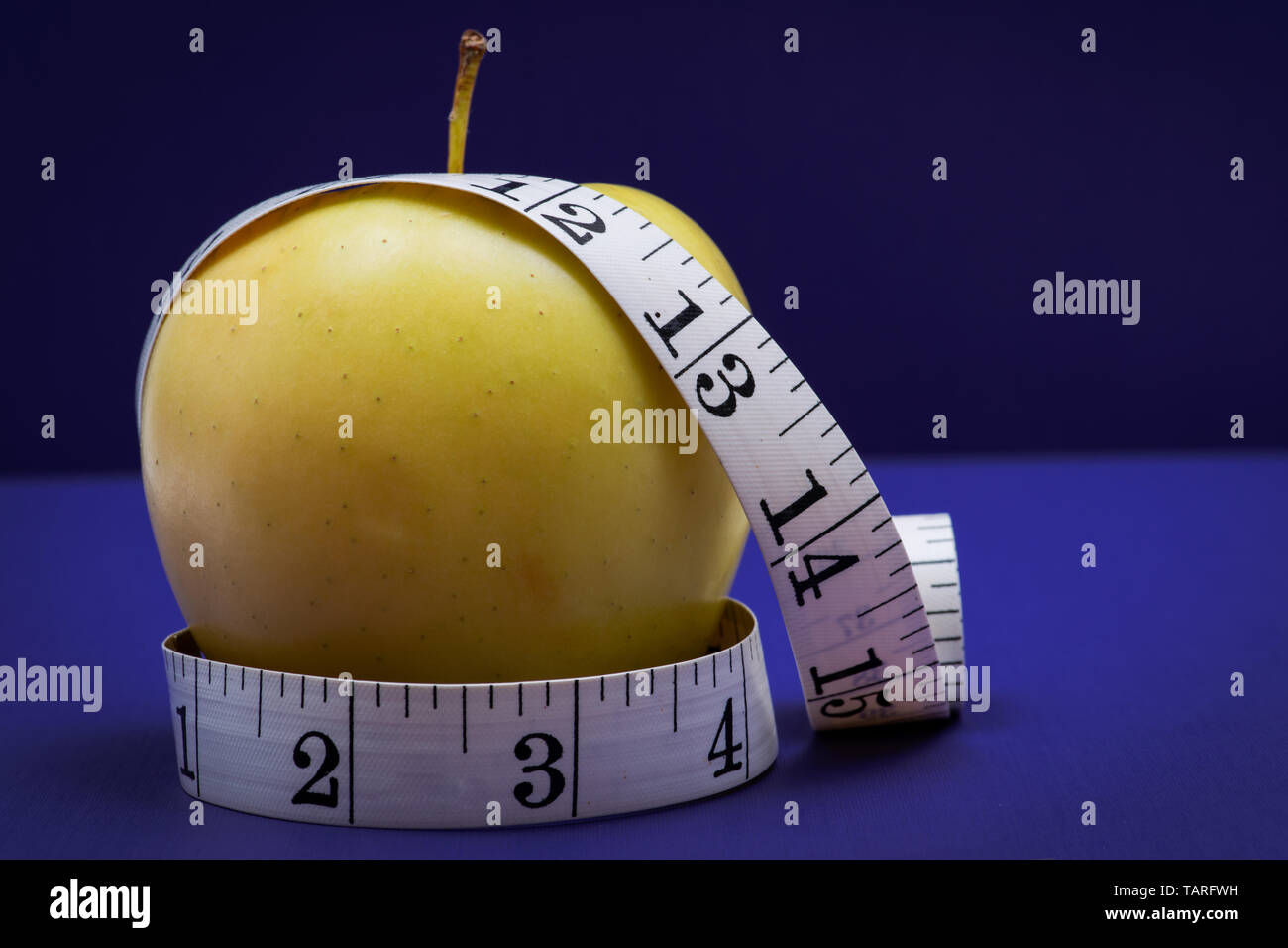 Gelber Apfel und weiches Vinyl Maßband auf lila Hintergrund. Stockfoto