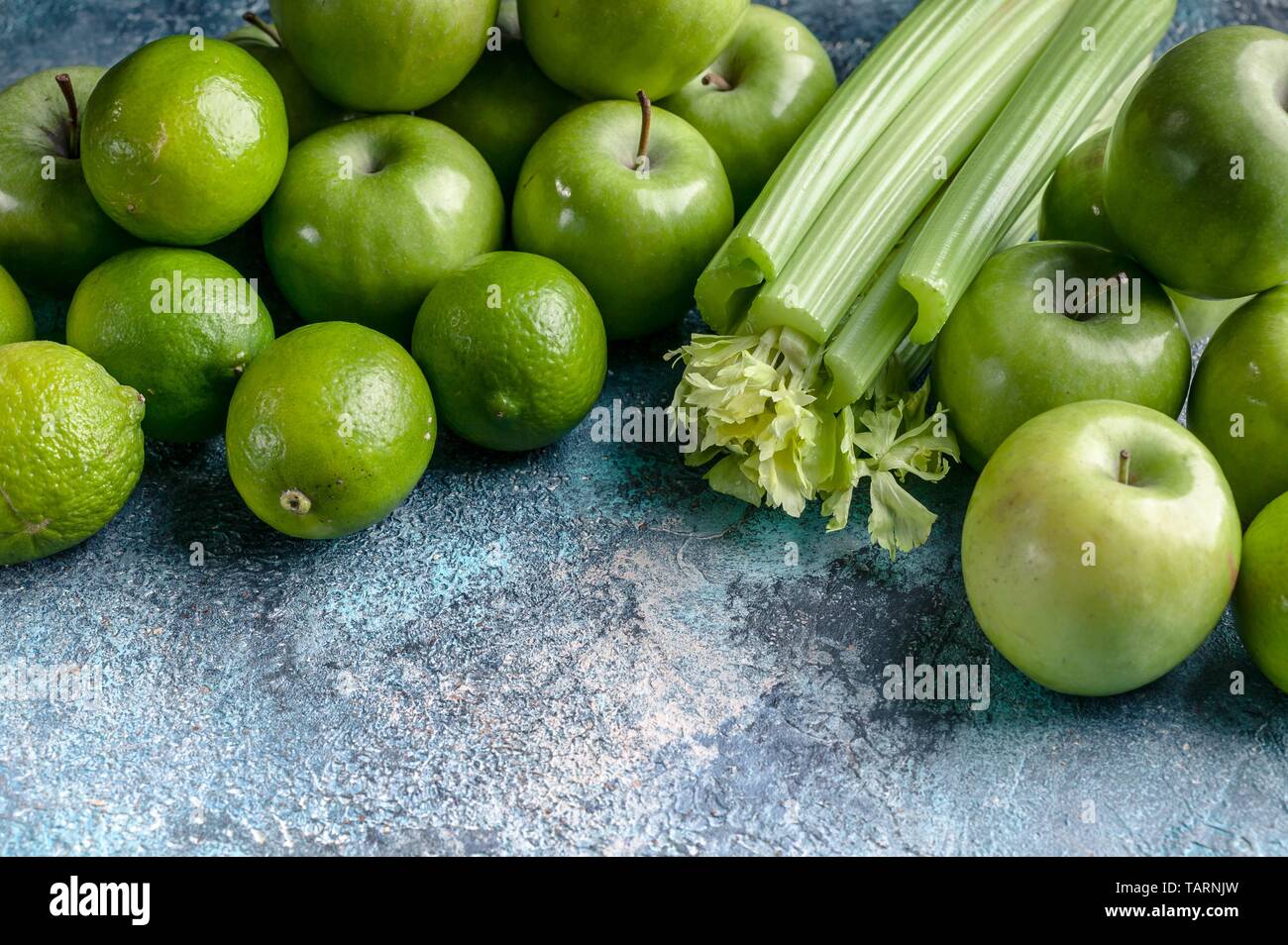 Grüne Äpfel, Sellerie und Limetten auf einen konkreten Hintergrund. Detox Programm, Diät, Gewichtsverlust. Flach Komposition. Stockfoto