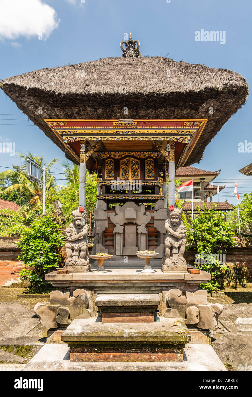 Dusun Ambengan, Bali, Indonesien - 25. Februar 2019: Eingerichtet grauen Stein Memorial Säule an clan Compound in Garten mit grünem Laub unter blauem Himmel Stockfoto