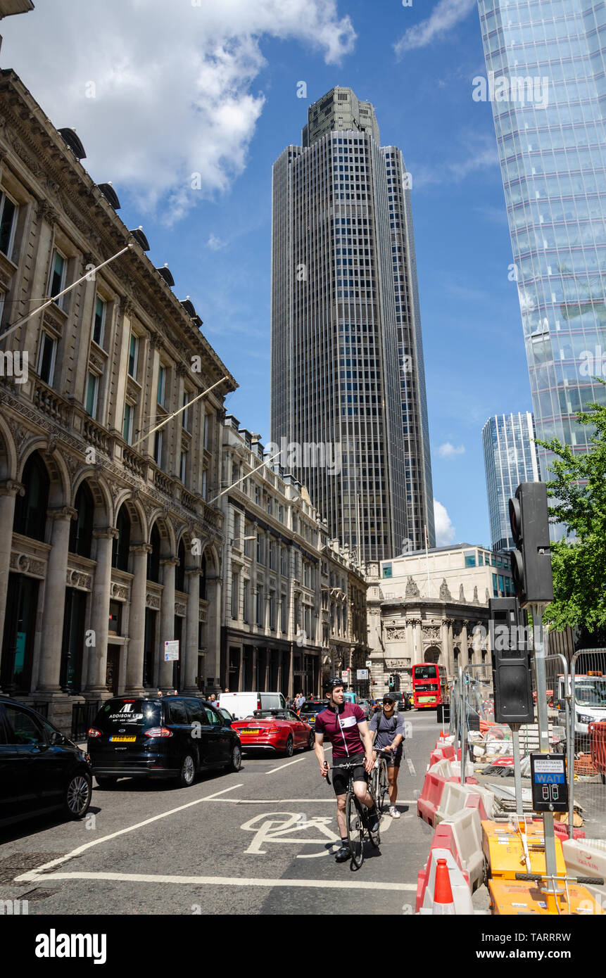 Blick auf Bishopsgate in London. Radfahrer konkurrieren mit dem Verkehr im Vordergrund, während Turm 42, ein moderner Wolkenkratzer, groß im Hintergrund steht. Stockfoto