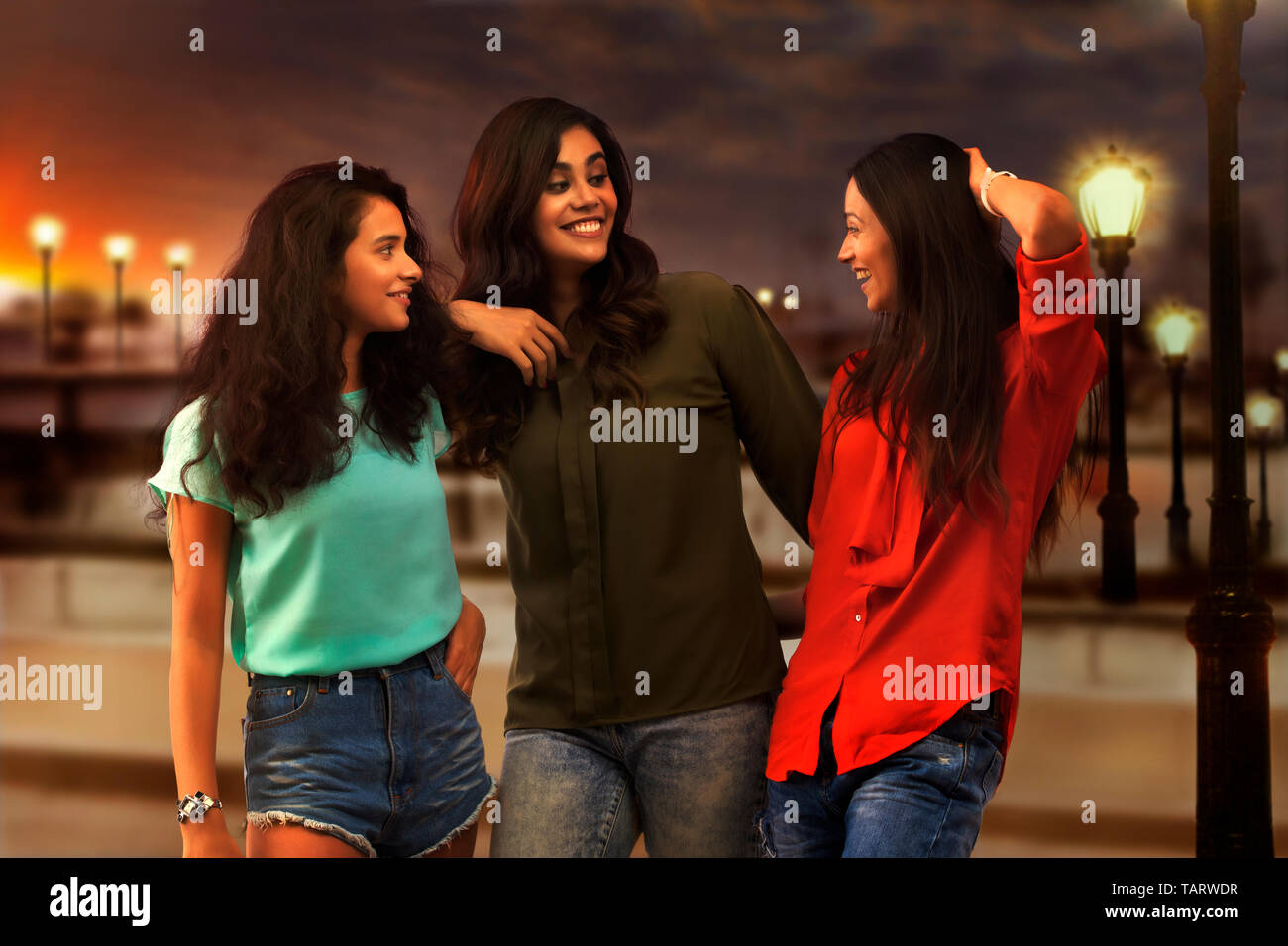 Drei Freundinnen stehen draußen in Abend und sprechen Stockfoto
