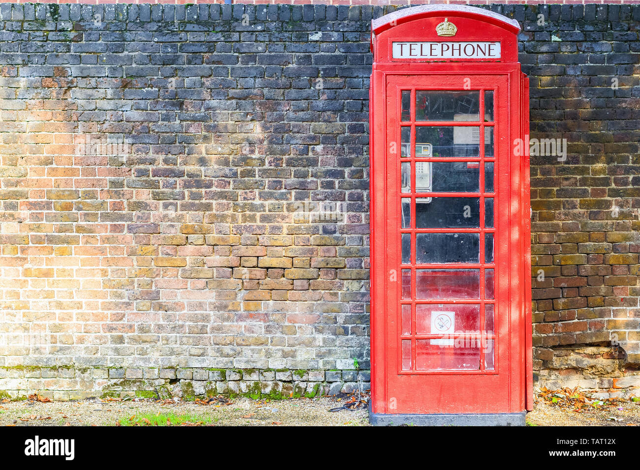 Traditionelle rote Telefonzelle auf der Straße von Hampstead Heath in London gegen ein grungy brick wall Stockfoto