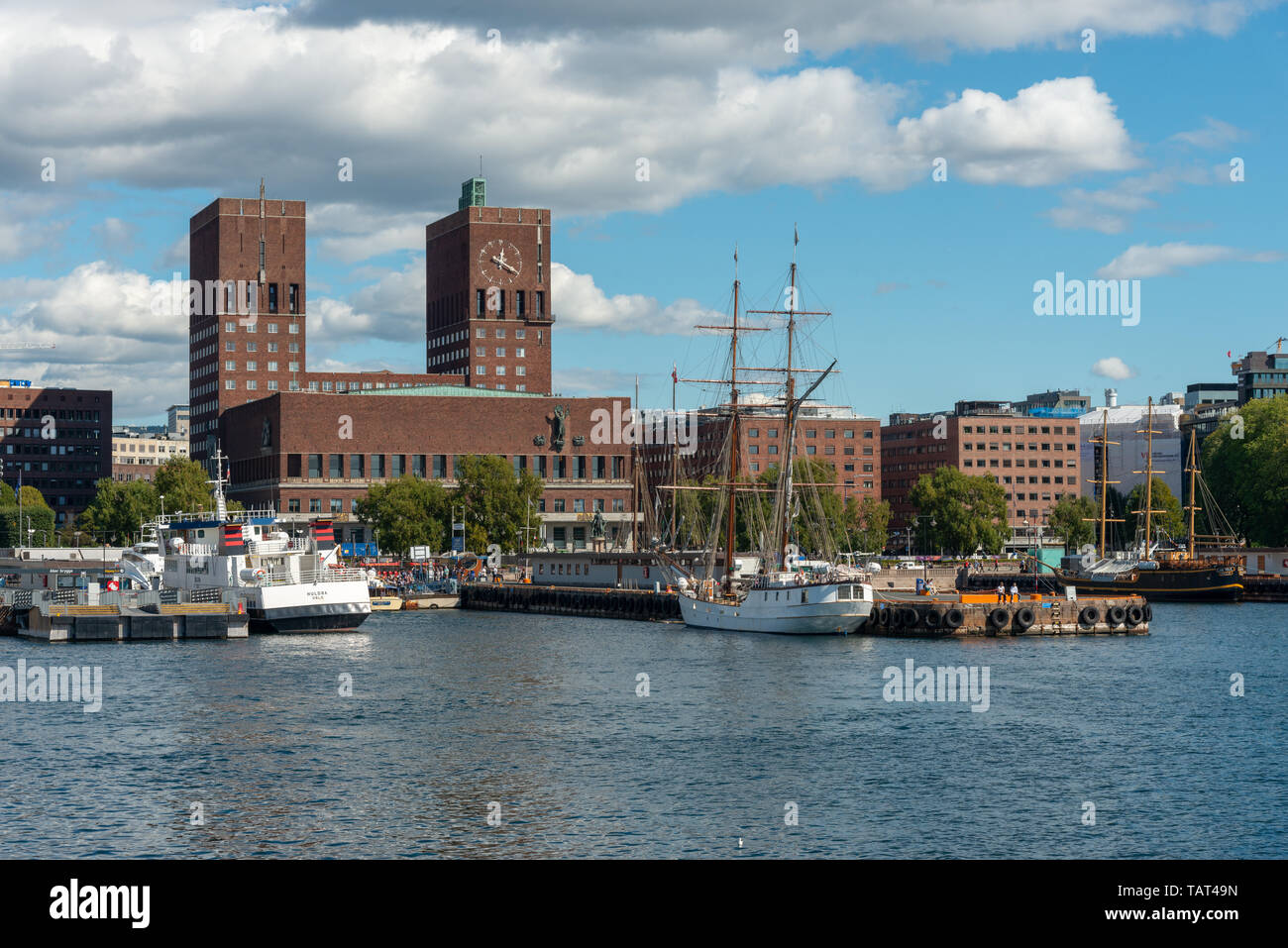 Aker Brygge [Boot], Fährterminal, Oslo, Norwegen. Oslo City Hall ist aus rotem Backstein gebaut und hat zwei Türme, einer 63 Meter hohen und 66 Meter hoch. Die Ziegel verwendet werden, größer als das, was typisch zum Zeitpunkt der Bau war, aber in etwa die gleiche Größe wie Backsteine im Mittelalter verwendet. Stockfoto