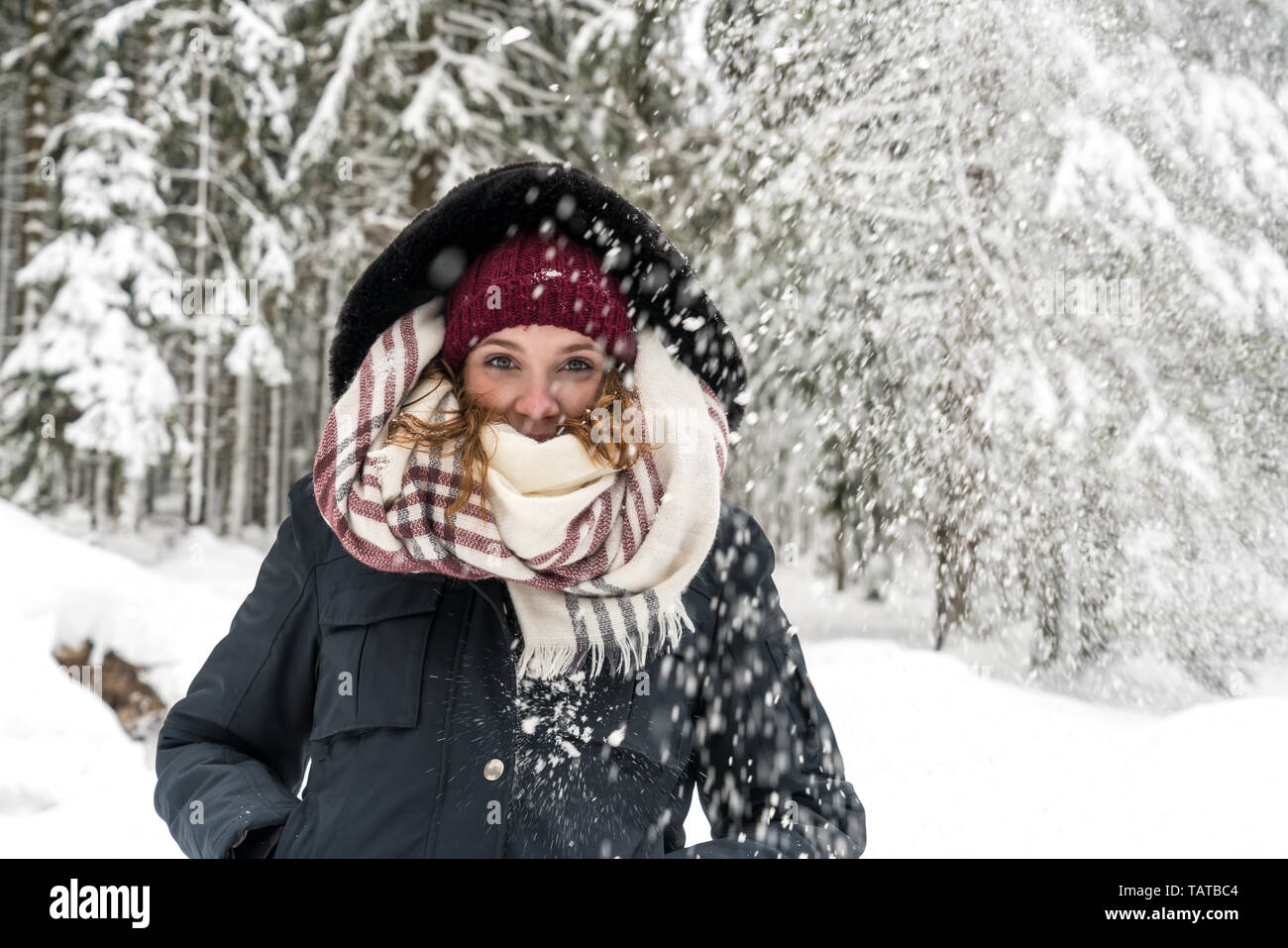 Eine junge Frau im Wald, während es schneit Stockfoto