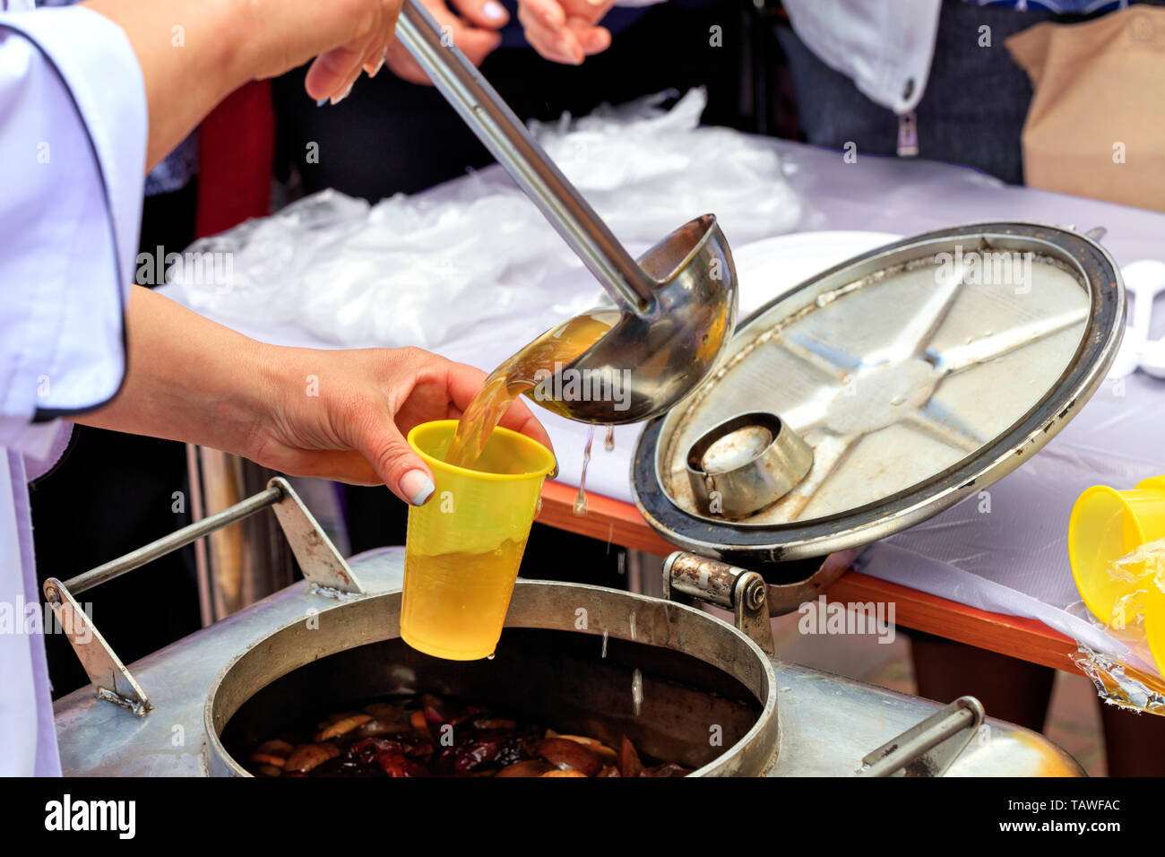 The concept of caring for the poor and the elderly: social workers feed people with fruit compote on the street. Stockfoto
