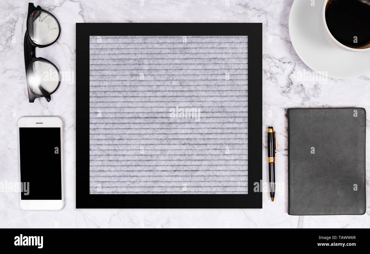 Freies Wort auf leeren Brief board in grauer Farbe auf weißem Marmor Schreibtisch Hintergrund mit Kaffeetasse, Notizbuch, Stift, Brille und Handy, flach c Stockfoto