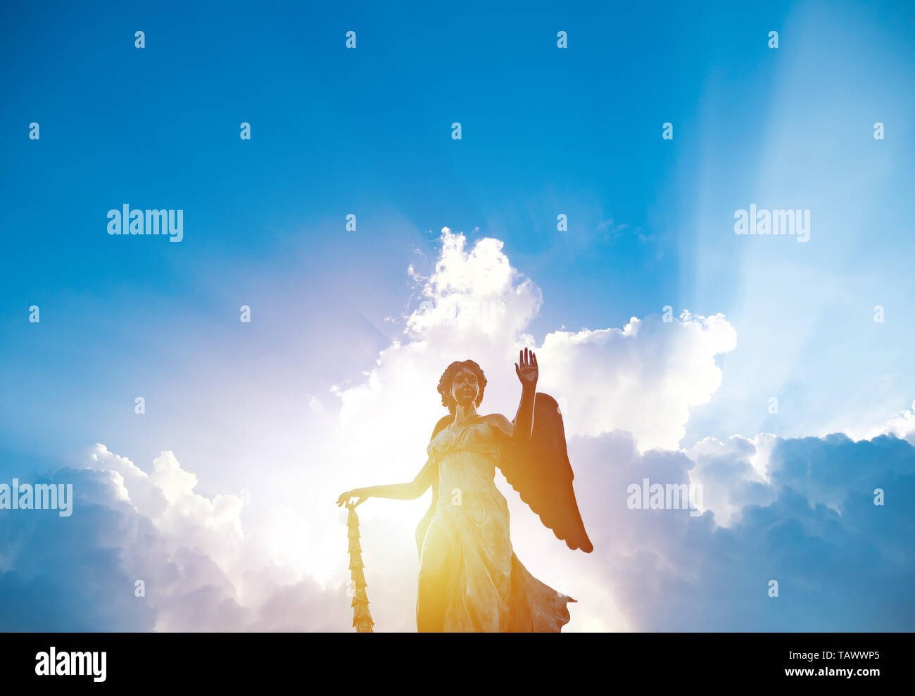 Silhouette der Engel Statue Skulptur mit Sonnenlicht hinter weißen Wolke mit blauem Himmel Hintergrund leuchtend Stockfoto