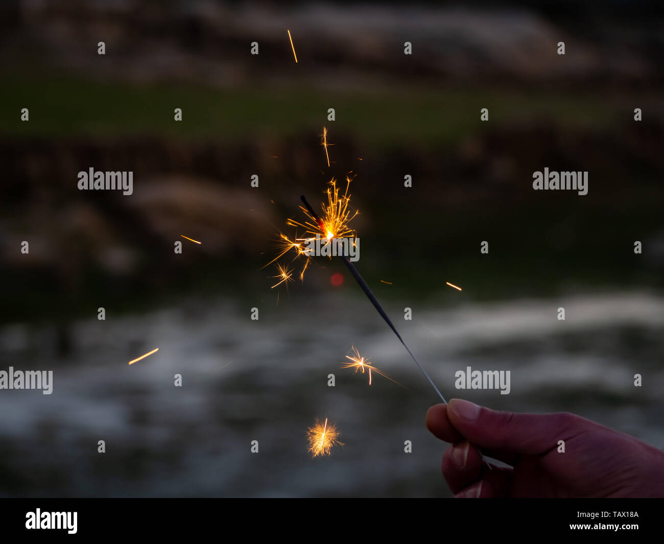 Eine nicht erkennbare Person mit einer Wunderkerze sizzling in seiner Hand. Stockfoto