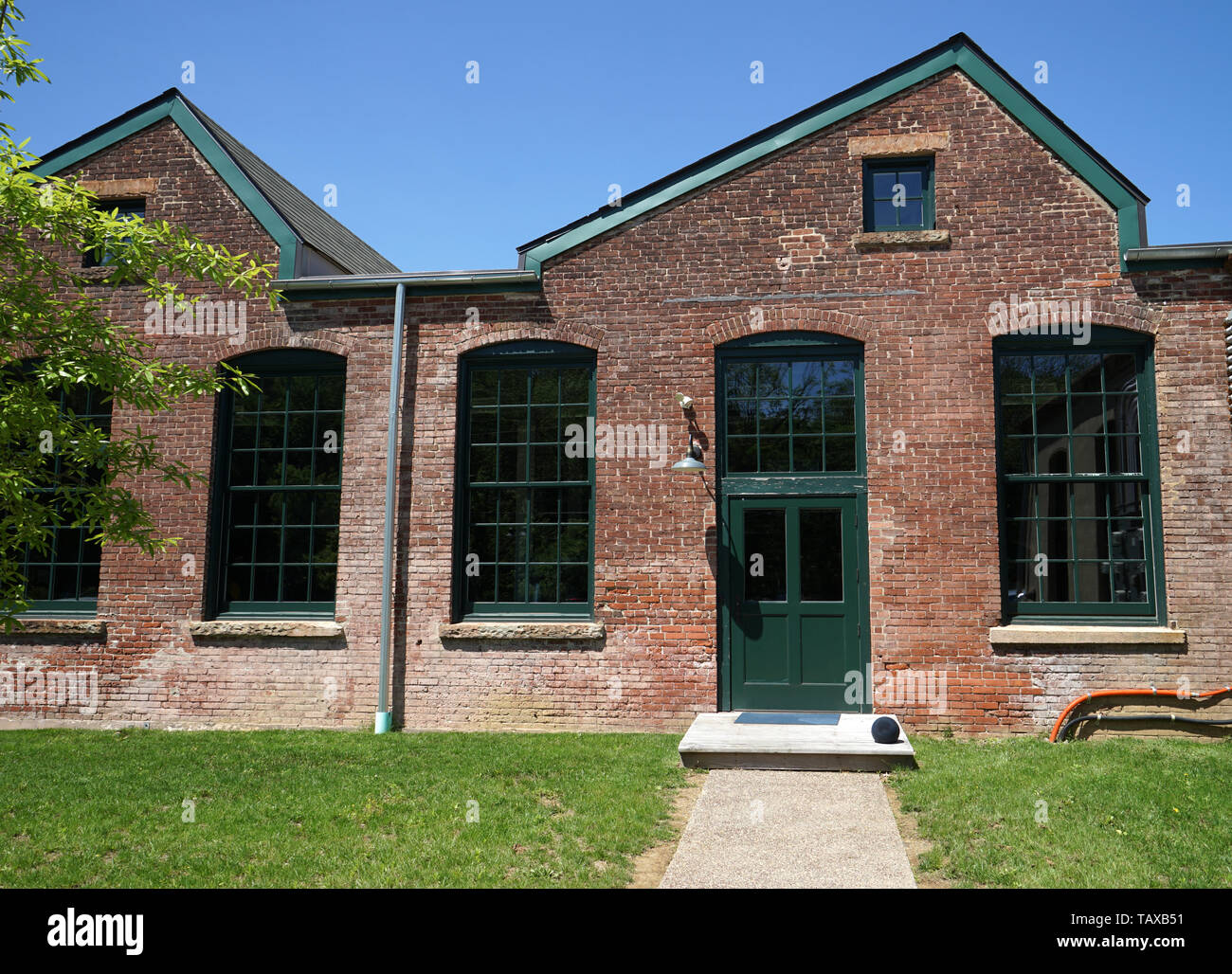 Fassade eines alten Seide Mühle. Die Fassade aus rotem Backstein, industrielle Türen und alten grünen Türen. Stockfoto