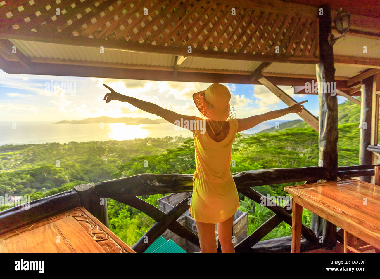 Carefree lifestyle Weiblich mit spektakulärem Blick auf den Seychellen und den Indischen Ozean bei Sonnenuntergang. Elegante touristische Frau im gelben Kleid betrachten Stockfoto