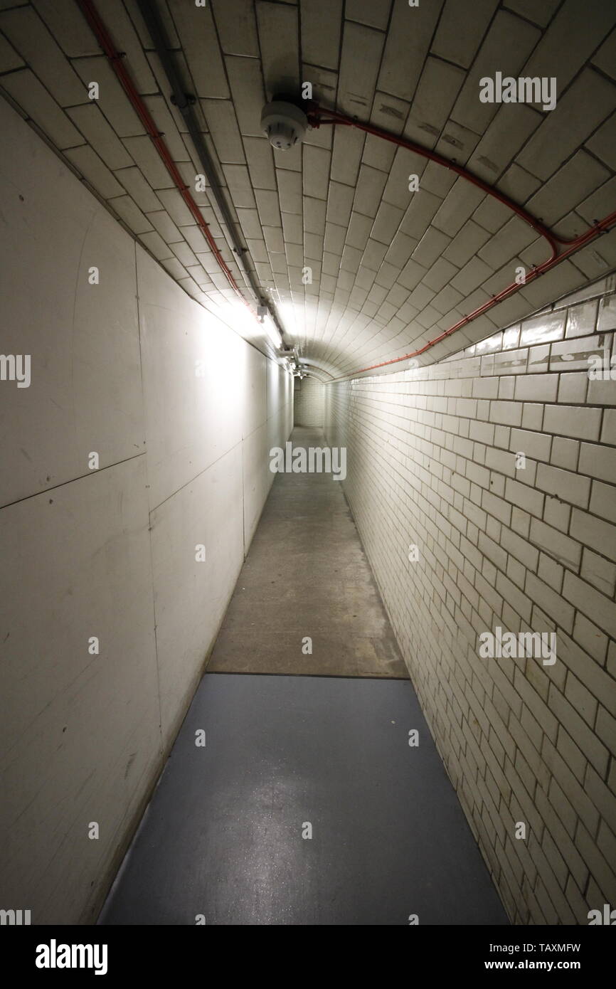Ein Blick entlang einer Kachel verglaste unterirdischen Fußgängertunnel mit eingeschränktem Platz. Am Ende des Tunnel verschwindet in der Ferne Stockfoto