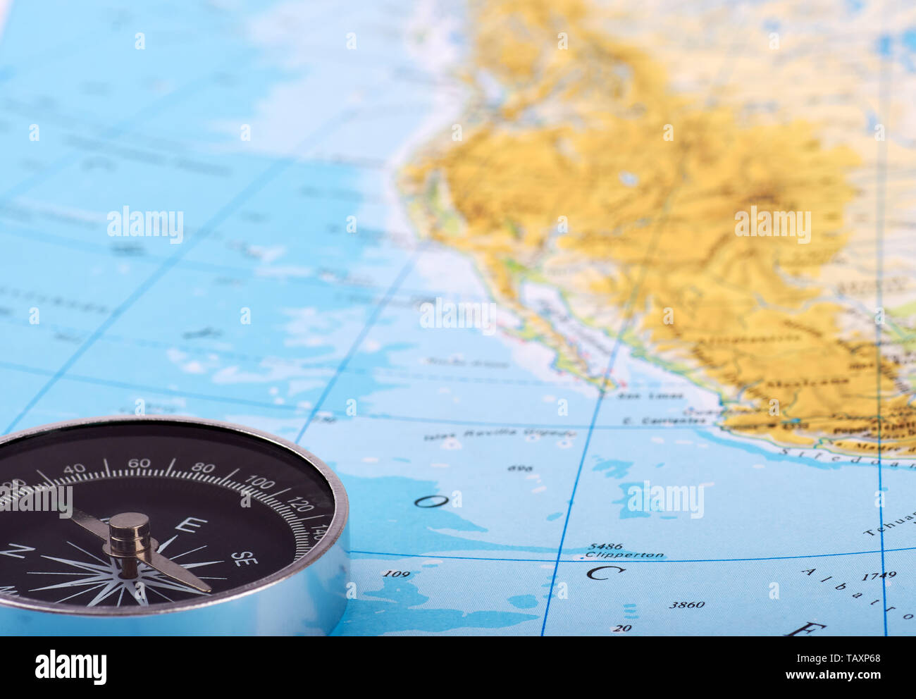 Detailansicht eines magnetischen Kompass auf einer Karte oder einem Atlas mit Blick aufs Meer oder Ozean. Geeignet für Reisen oder Urlaub. Stockfoto