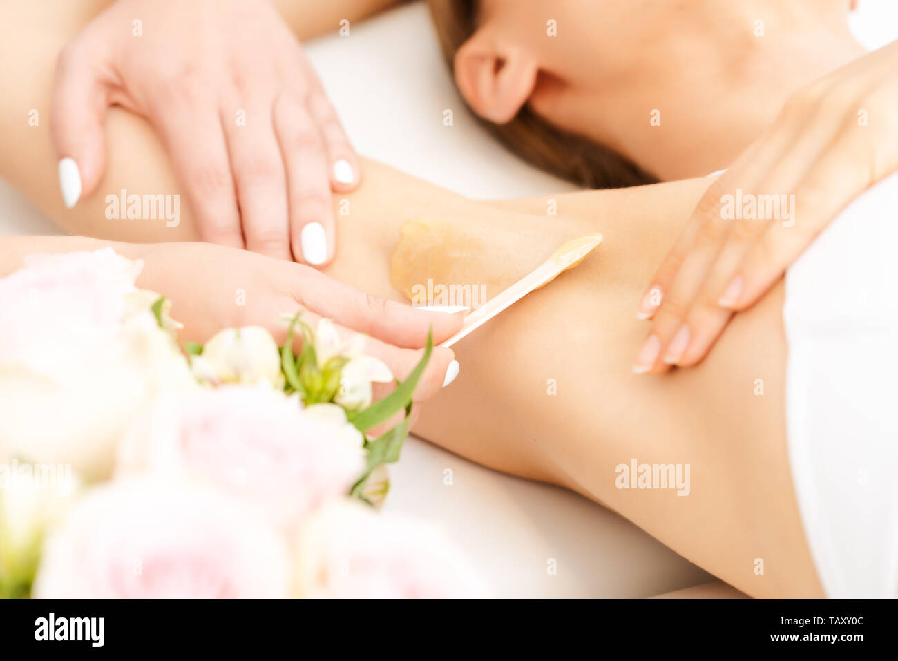 Haarentfernung mit zuckerpaste in einem Schönheitssalon Stockfoto