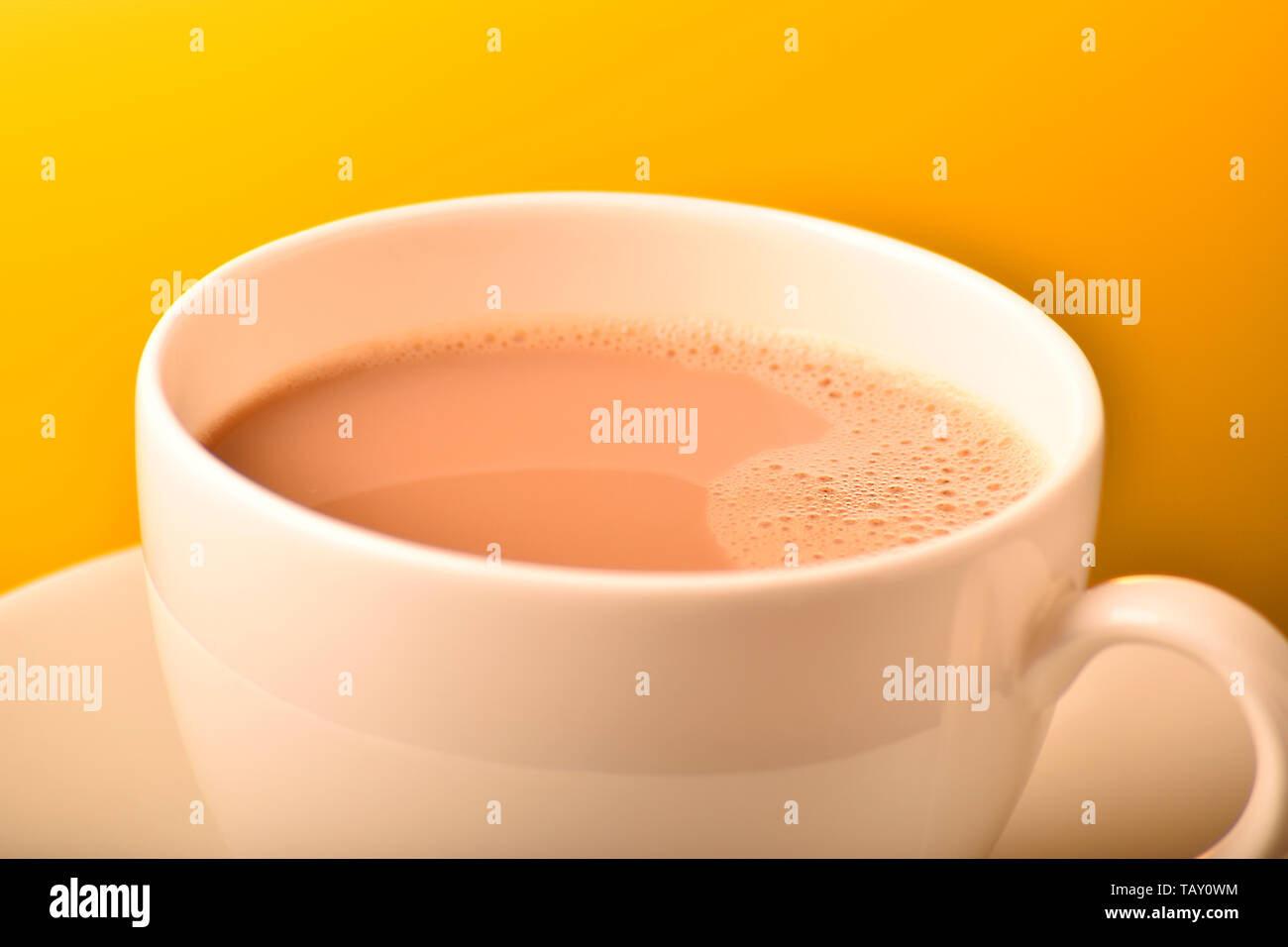 Milch Kaffee in Weiß ceremic Cup gegen gelben Hintergrund Stockfoto