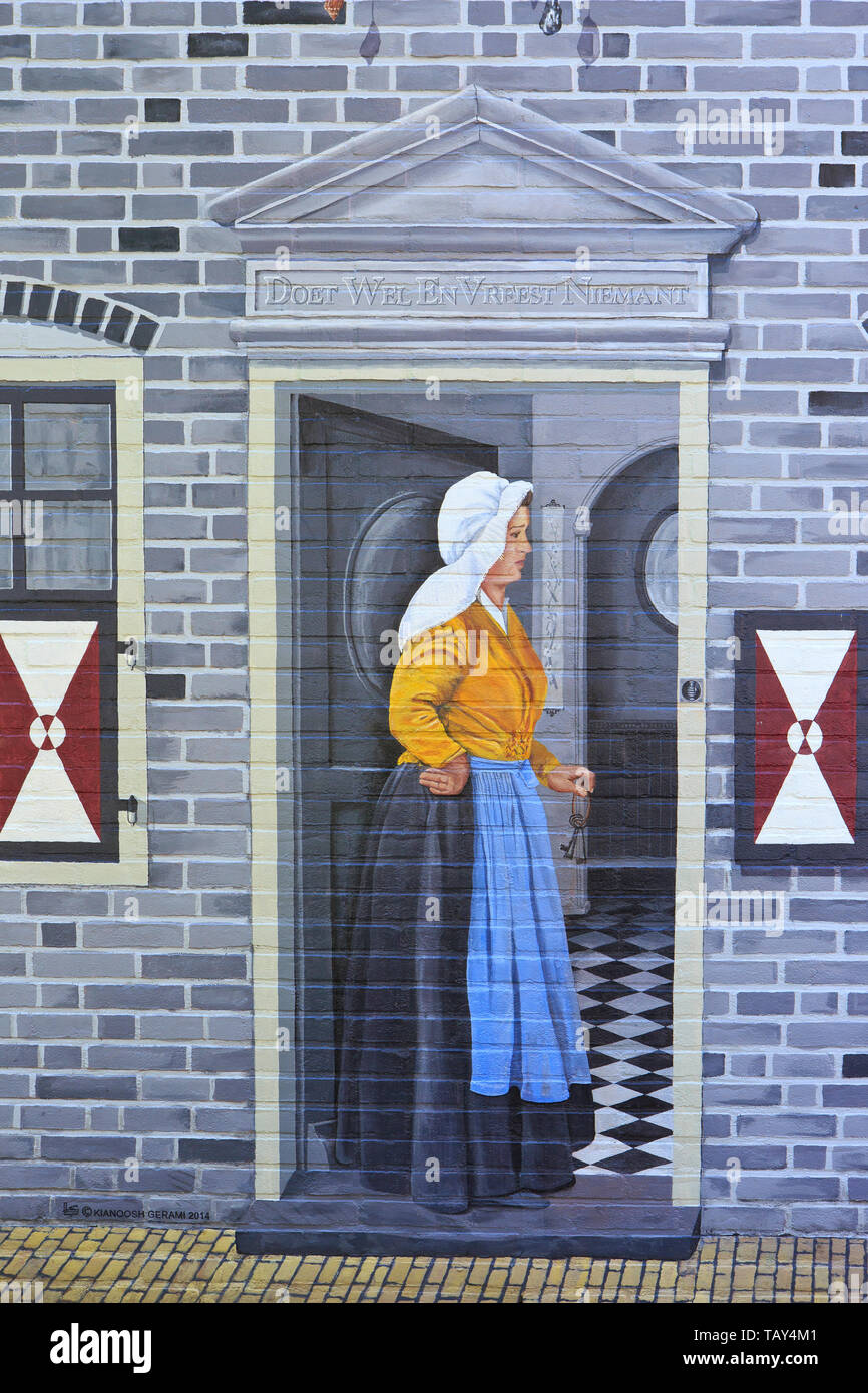 Eine Dame in einem traditionellen Kleid am Eingang ihres Hauses auf einer Graffiti/Wandmalerei/Mural in Zierikzee (Zeeland), Niederlande Stockfoto