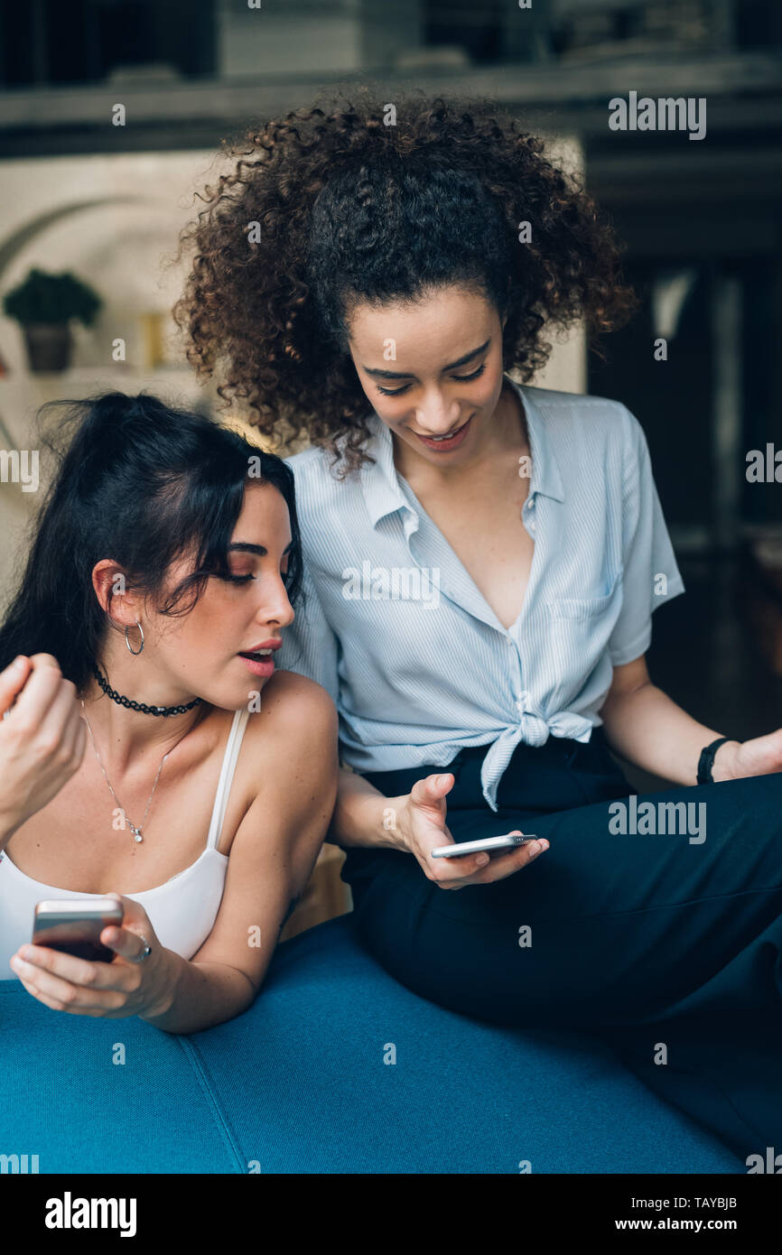 Zwei jungen kaukasischen Frauen Interaktion mit Smartphone - Technologie, das Miteinander, die Freundschaft Stockfoto