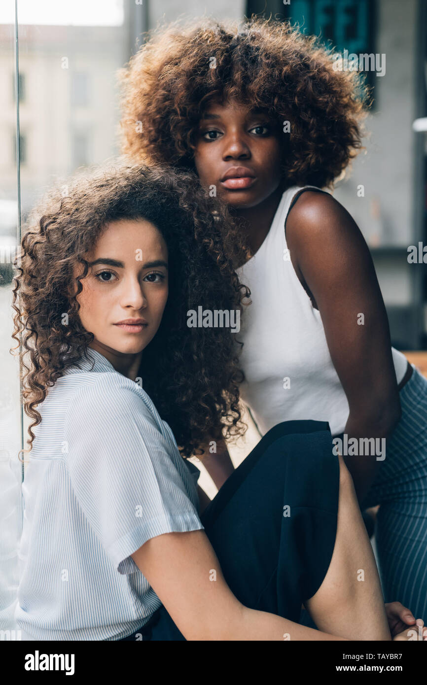 Zwei Jungen multiethnischen und lockigen Frauen zusammen Posieren auf der Suche Kamera - Jugend, neue Generation, phantasievolle Stockfoto