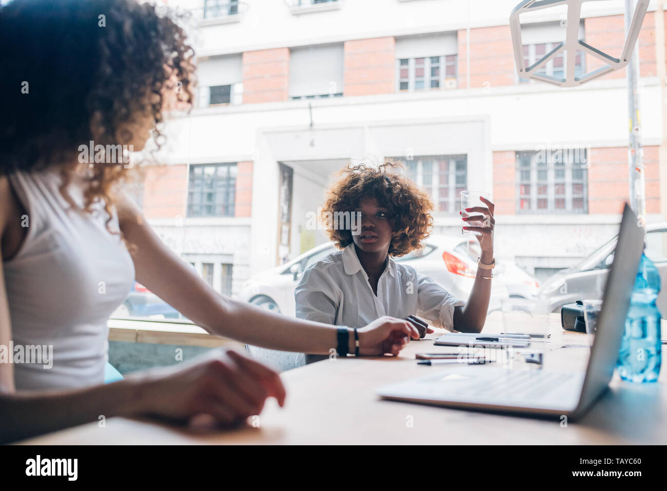 Zwei junge Unternehmerinnen in Talk im modernen Büro - Interaktion, Kreativität, ehrgeizig Stockfoto