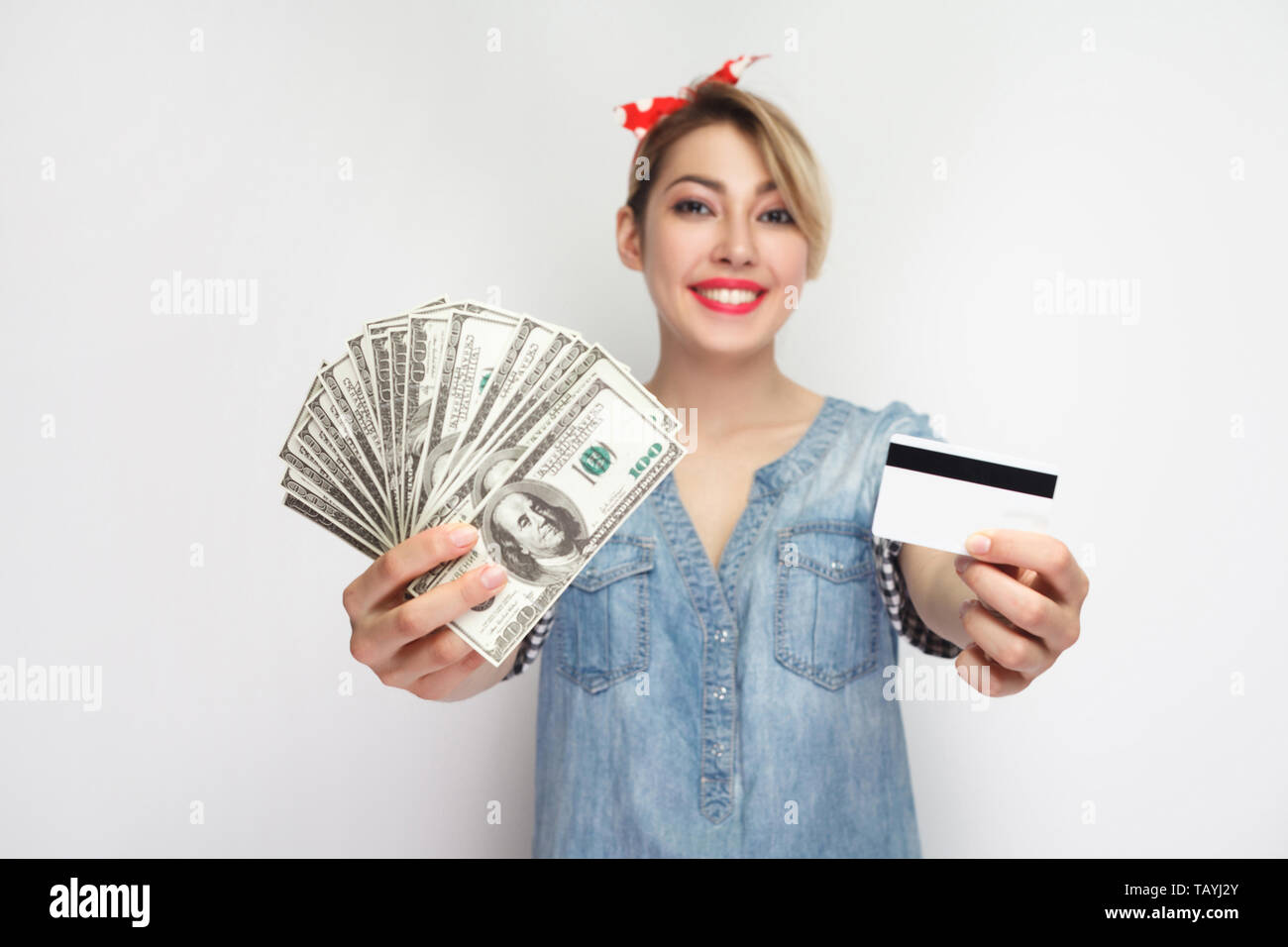 Wahl für Usability bar oder mit Karte. Junge Mädchen in lässigem Blue Denim shirt stehend, Bargeld und Kreditkarte für Auswahl, toothy Lächeln zeigen. Ich Stockfoto