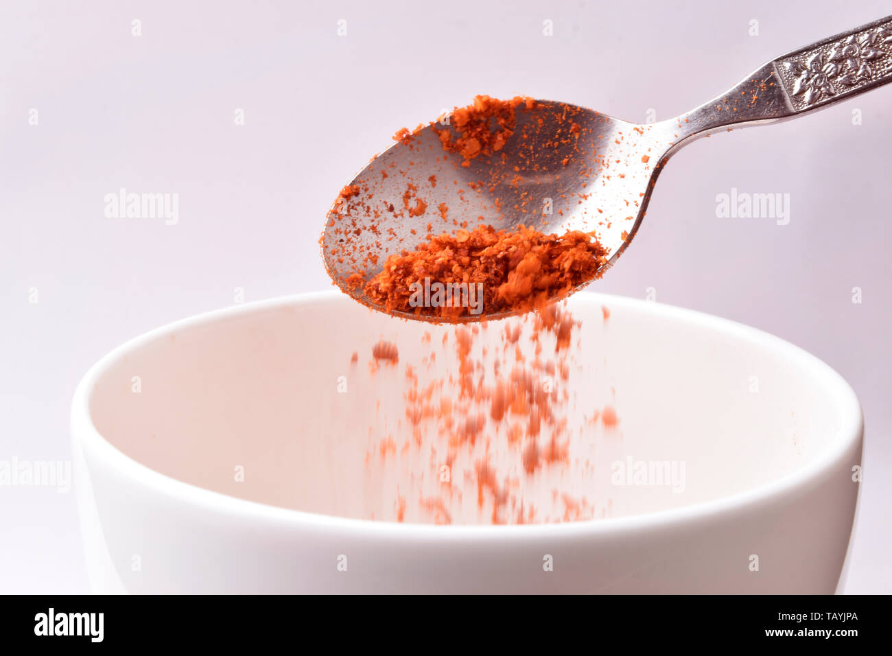 Edelstahl Löffel von red chili Pulver in Weiß Schüssel auf weißem Hintergrund-Bild Stockfoto