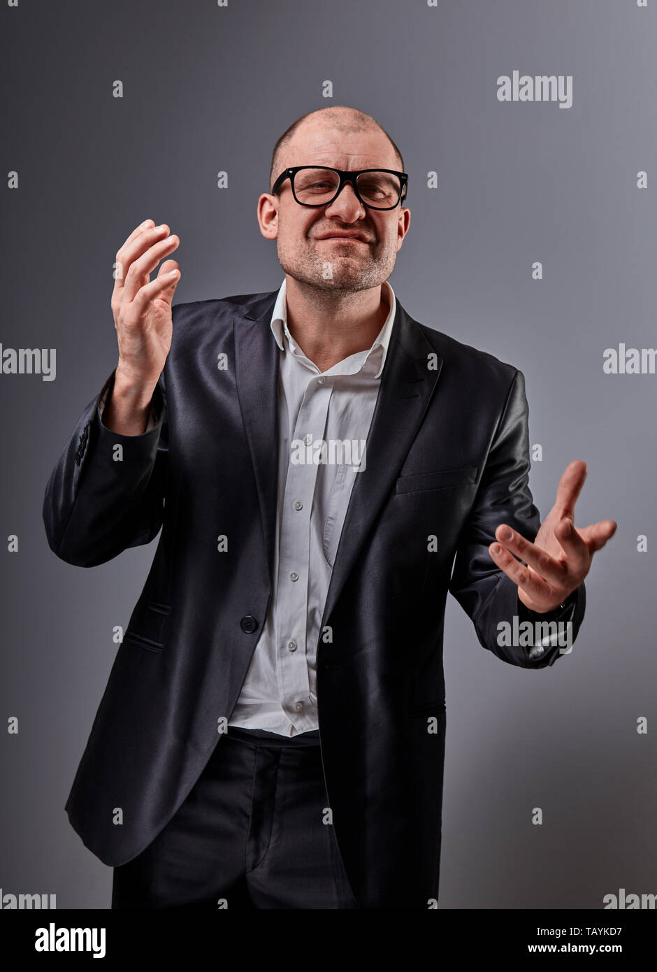 Denken böse Glatze business Mann in Brillen und Anzug erklären und Bewegen  der Hände auf grauem Hintergrund. Nahaufnahme Stockfotografie - Alamy