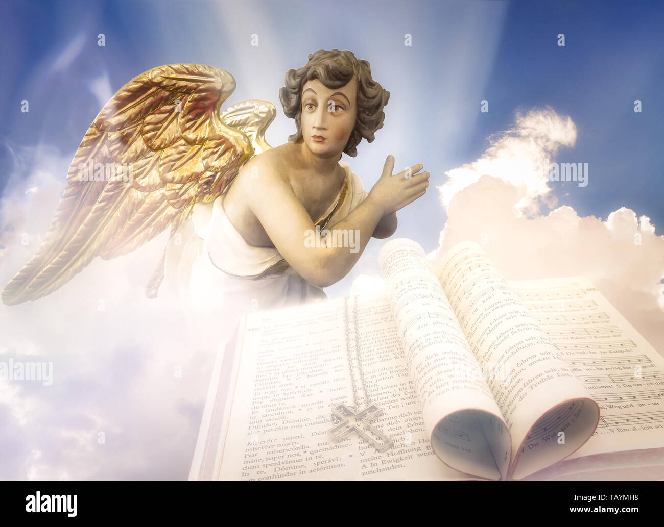 Beten Engel mit goldenen Flügeln in den Himmel mit einem katholischen Gesangbuch Stockfoto