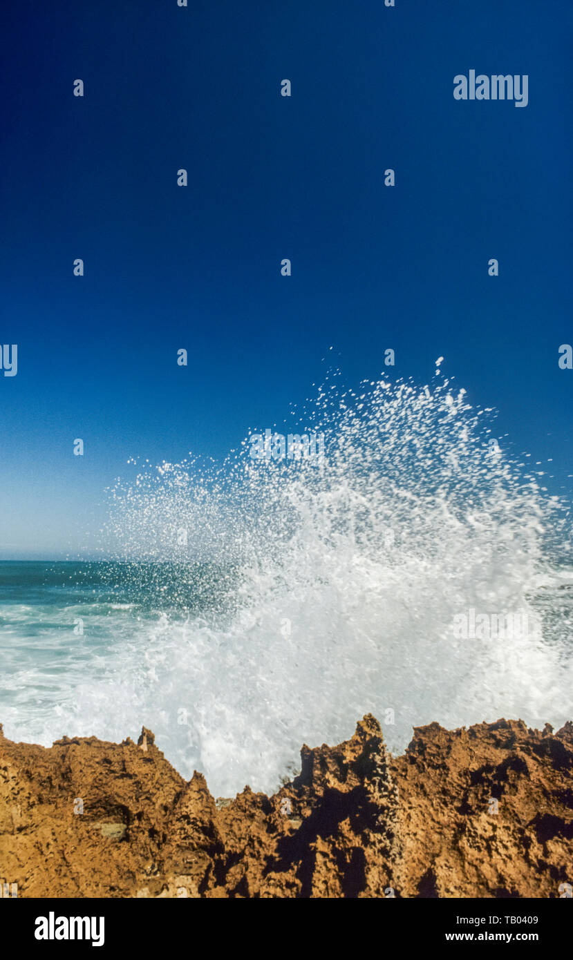 Große Welle über felsige Küstenlinie explodierende Stockfoto