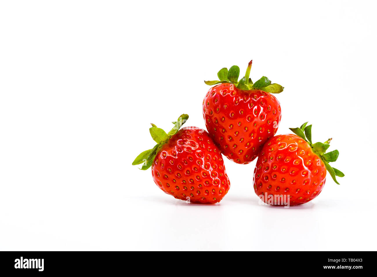 Nahaufnahme von drei reife Erdbeeren Balancieren auf einander. Alle sind gegen einen weißen Hintergrund mit Platz für Kopie auf der rechten Seite isoliert. Stockfoto