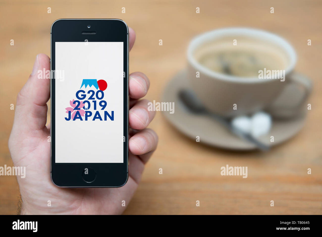 Ein Mann schaut auf seinem iPhone die zeigt die G 20 2019 Osaka Japan Gipfel Logo (nur redaktionelle Nutzung). Stockfoto