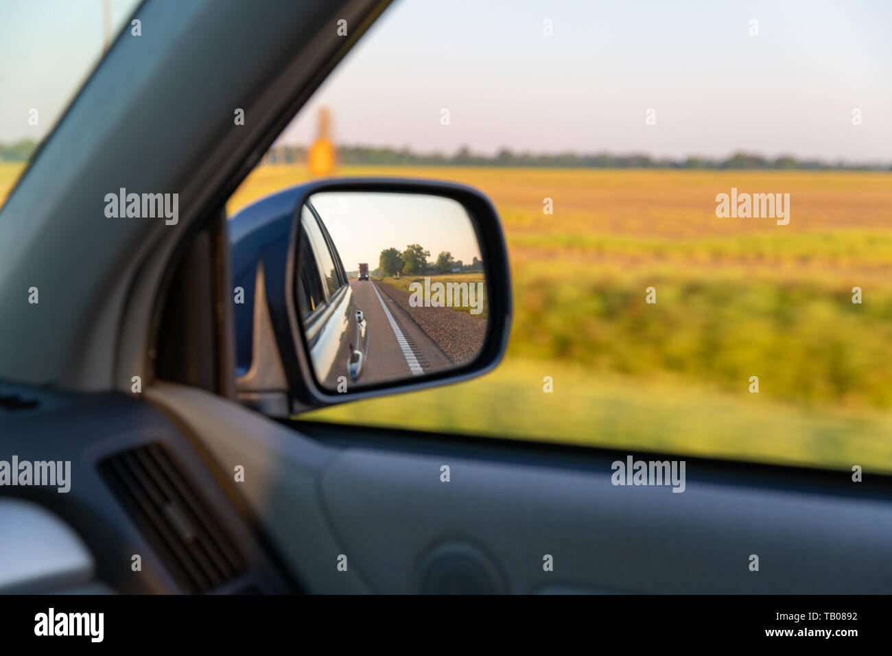 Blick aus dem Auto und Rückspiegel im ländlichen Ackerland, während der Fahrt auf der Autobahn im Süden von Amerika. Stockfoto