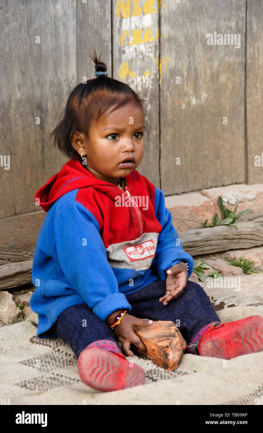 Junge Kind spielt mit Backstein auf Stoop von zu Hause in Altstadt Dhulikhel, Nepal Stockfoto