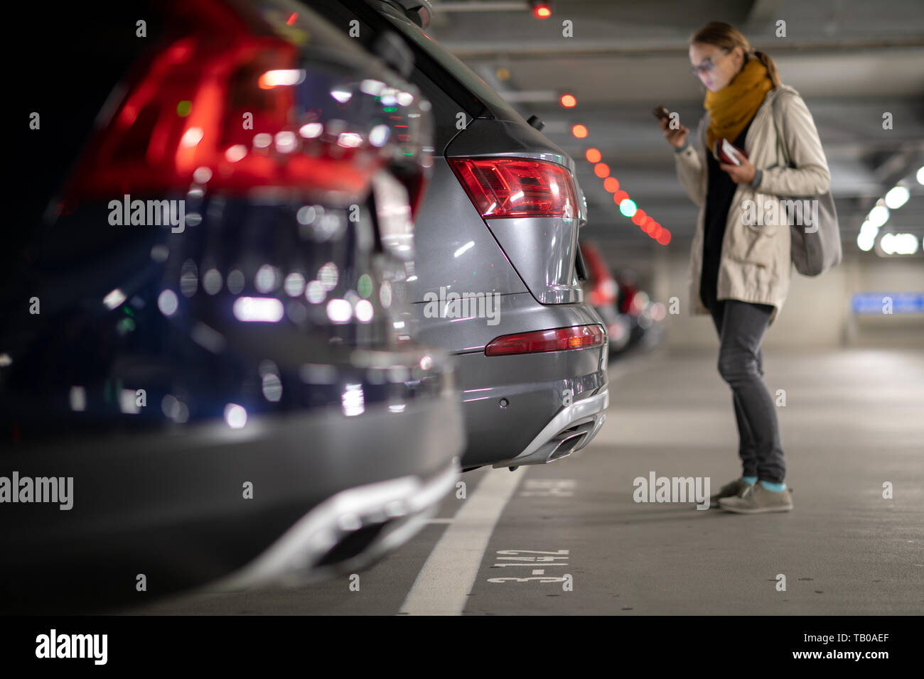 Tiefgarage oder modernen Parkplatz mit vielen Fahrzeugen, die Perspektive der Reihe der Autos mit einem weiblichen Fahrer auf der Suche nach Ihrem Fahrzeug Stockfoto