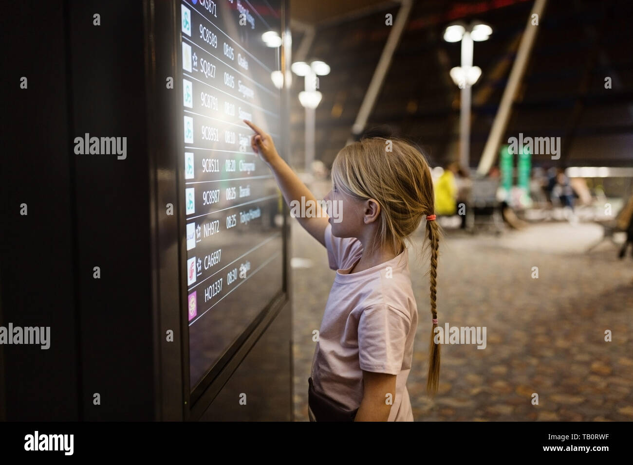 Süße kleine Mädchen durch Drücken auf das Symbol Digital Touchscreen im Flughafen Terminal. Blonde Mädchen mit Technologie Stockfoto