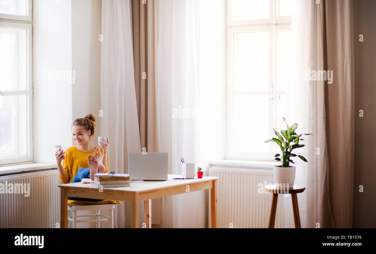 Eine junge Schülerin am Tisch sitzend, über smartpone können beim Studium. Stockfoto