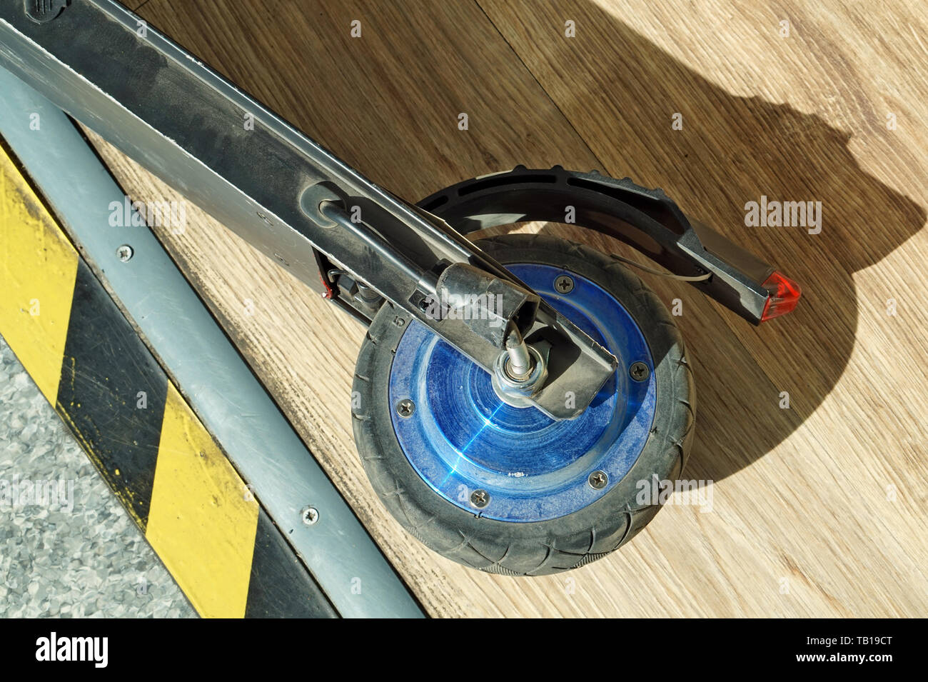 Gebrochen Rad von einem kleinen, modernen elektrischen scooter auf dem Hintergrund einer Holzboden Stockfoto