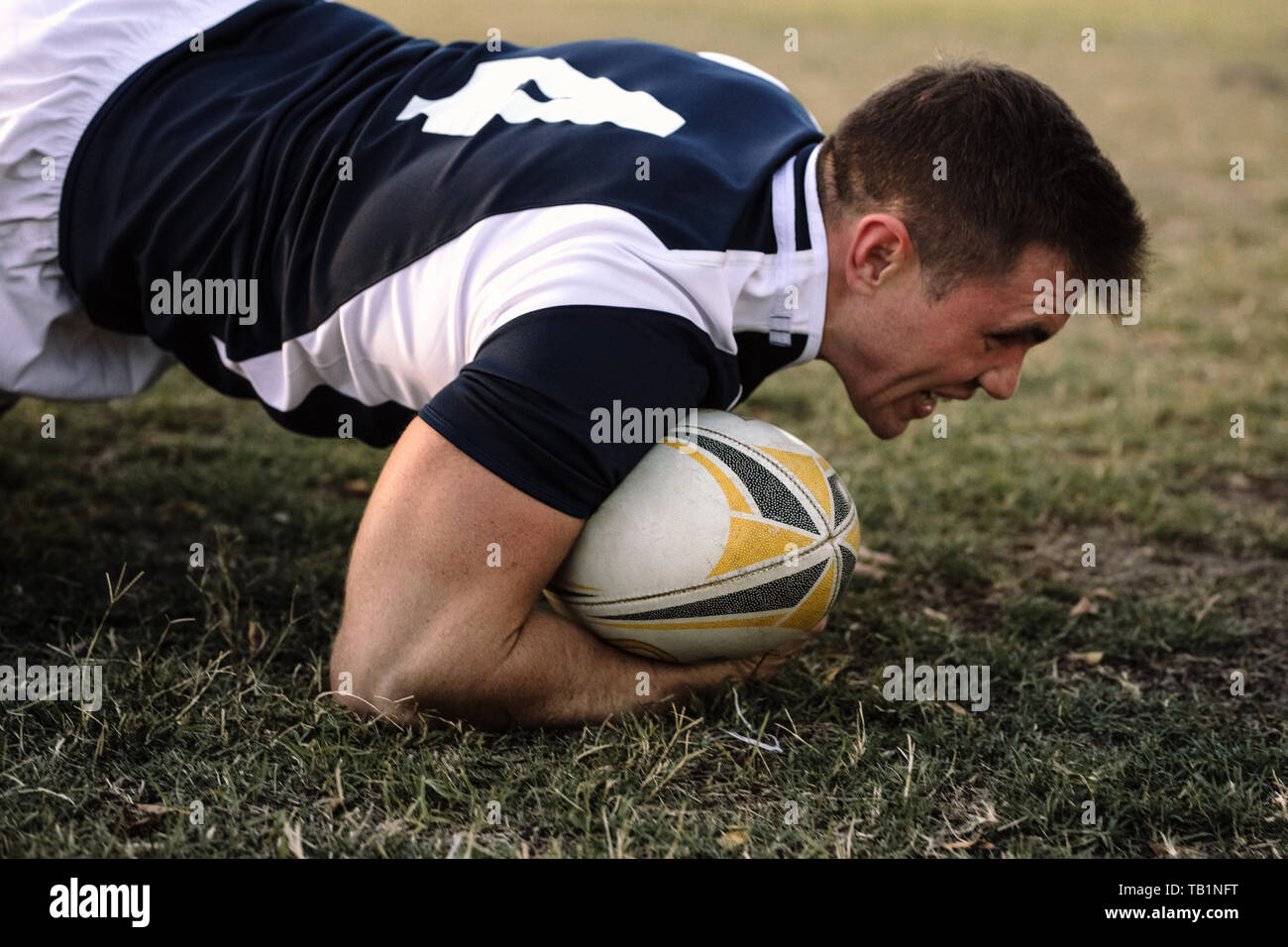 Starker Rugbyspieler mit Ball auf dem Boden während des Spiels. rugbyspieler mit Ballbesitz im Spiel. Stockfoto