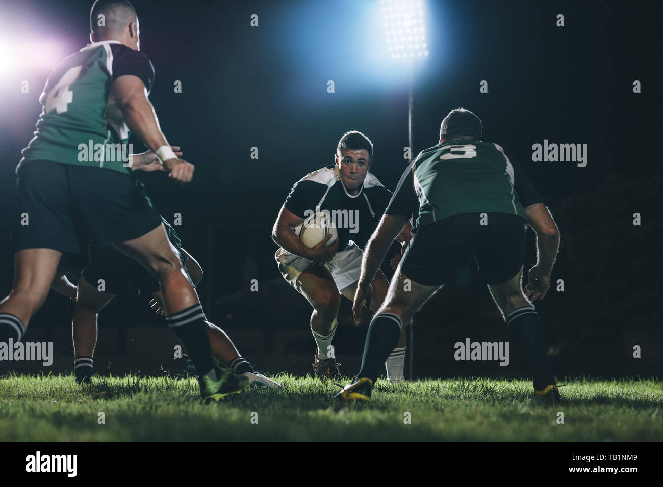 rugbyspieler, der mit Ball auf dem Feld läuft und während des Spiels mit anderen Teamspielern in Angriff genommen wird. Profi-Rugby-Action bei Sportarten Stockfoto