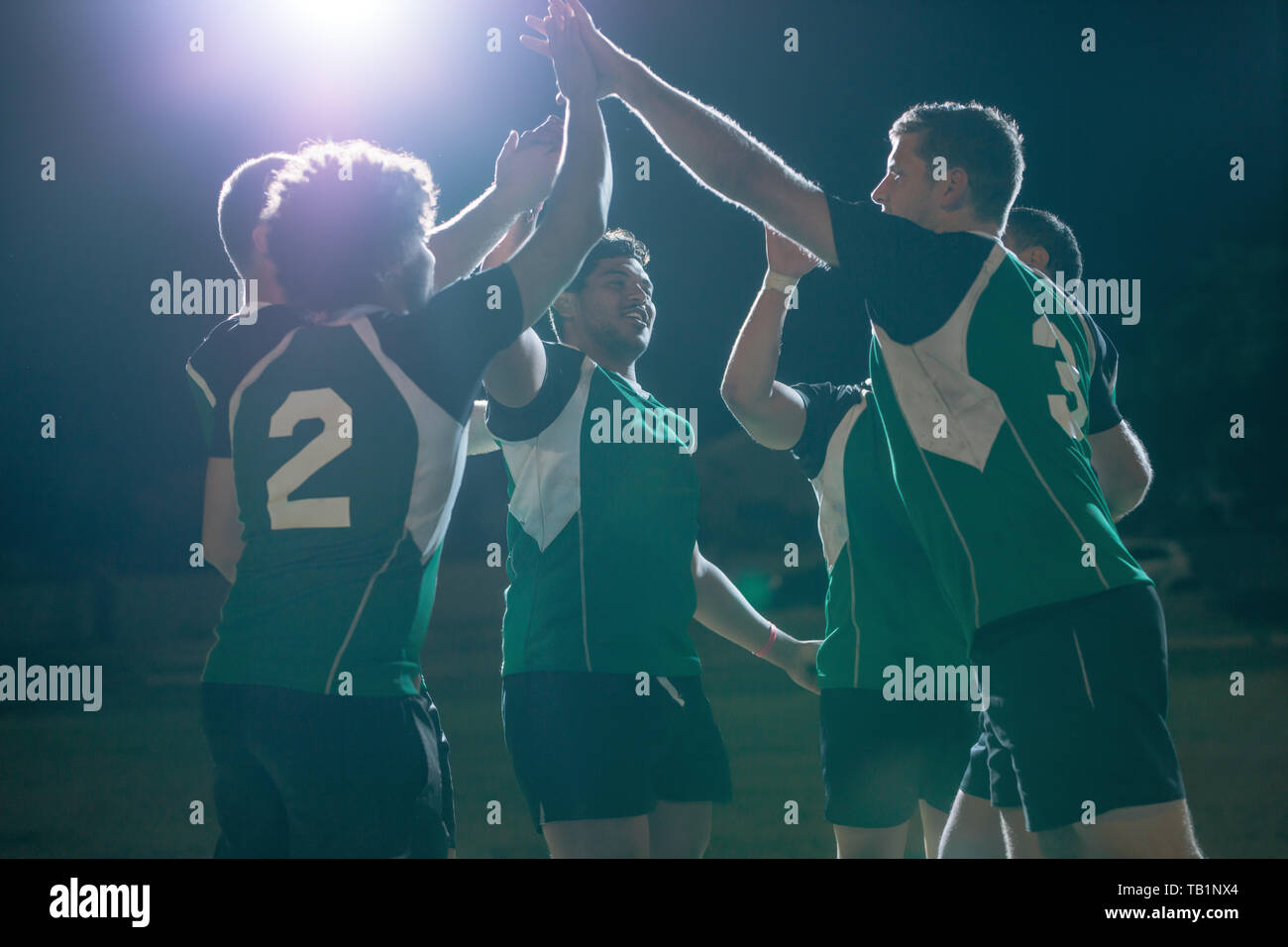 Das rugby-Team hat nach dem Sieg unter Licht die Hände zusammengelegt. rugby-Spieler feiern Meisterschaftsgewinn. Stockfoto
