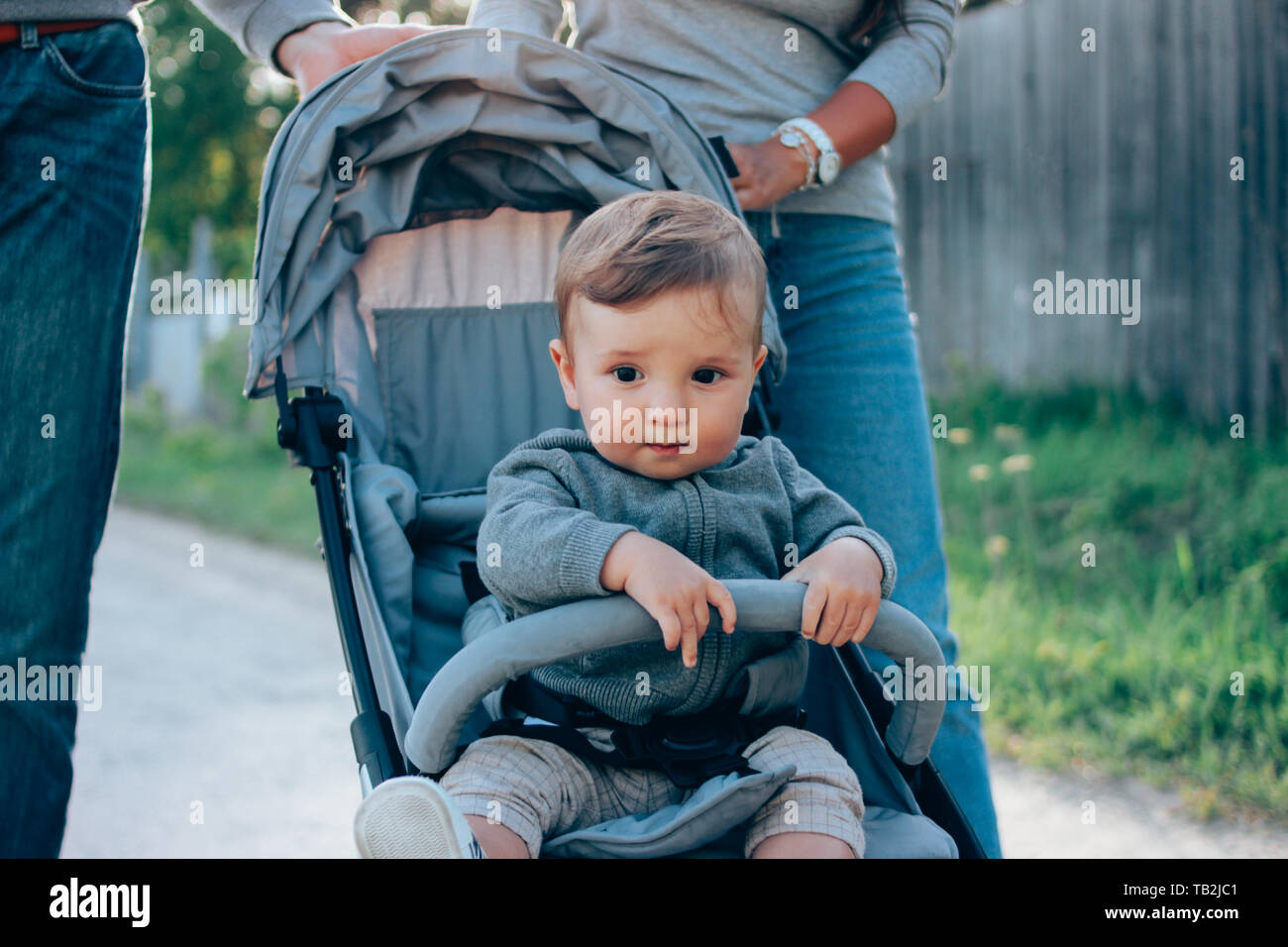 Cute Baby Boy 8-9 Monate sitzen in Buggy mit Papa und Mama zu Fuß auf der  Dorfstraße im Freien, Sensibilität für die Natur Konzept Stockfotografie -  Alamy