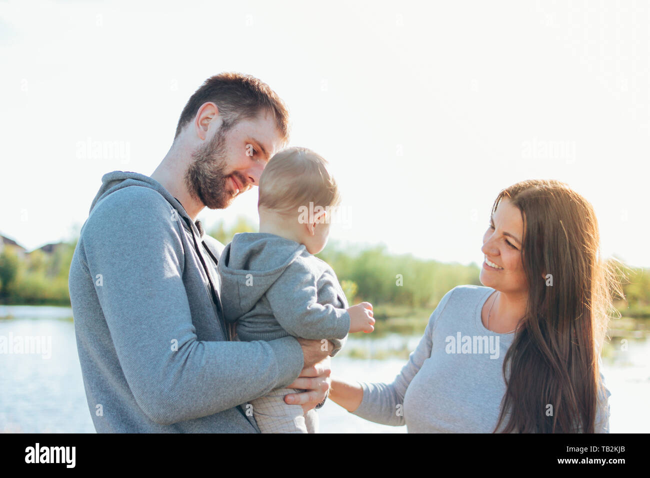 Glückliche Familie mit niedlichen Baby auf See Wasser Hintergrund im Freien, Sensibilität für die Natur Konzept Stockfoto