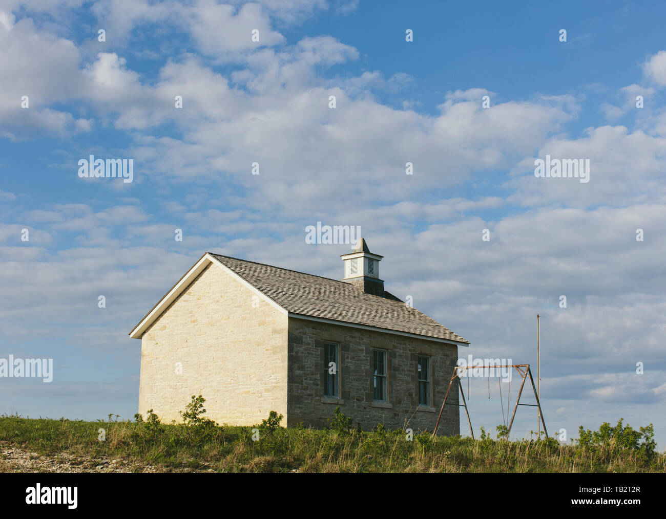 Tallgrass Prairie Preserve, einem historischen Schule Haus Gebäude und einer Pappel Baum und eine Reihe von rostigen Schaukel, im Frühling. Stockfoto