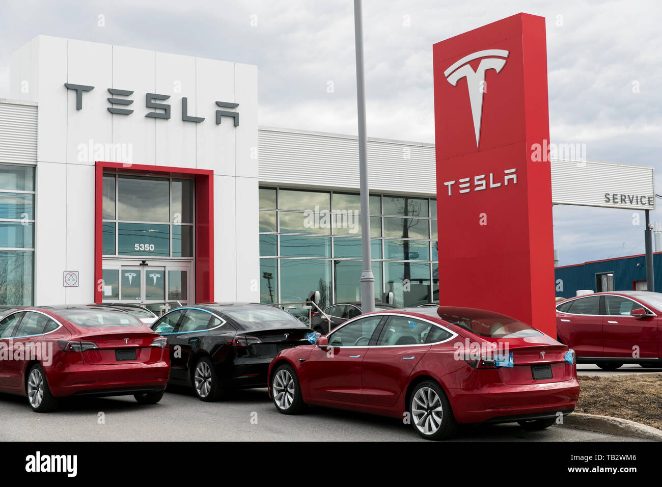 Ein logo Zeichen außerhalb eines Tesla Autohaus mit Modell 3 und Modell S Autos auf dem Parkplatz in Montreal, Quebec, Kanada, am 21. April 2019. Stockfoto