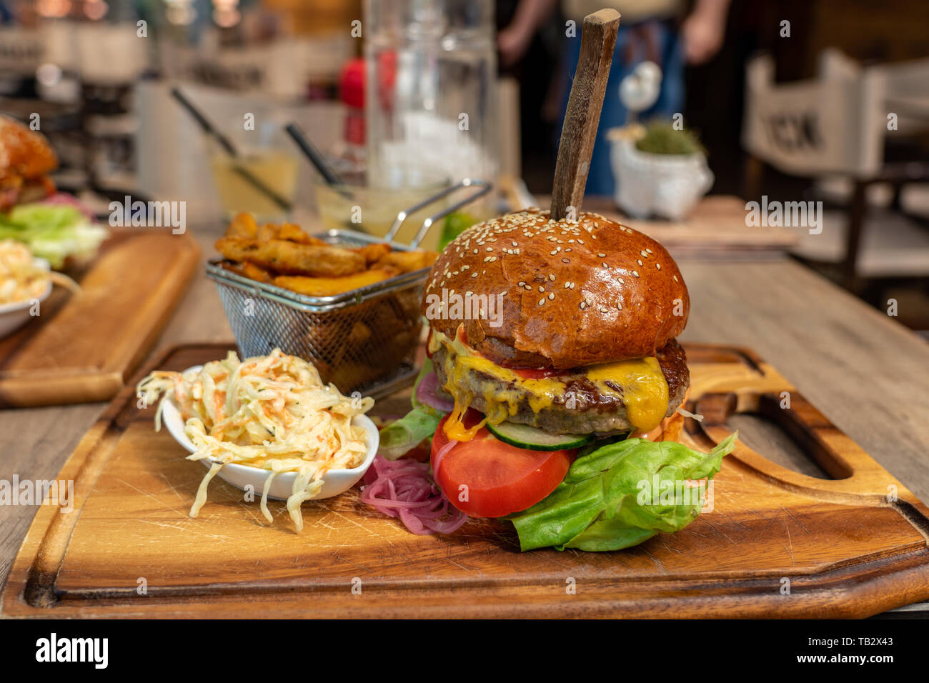 Essen zwei Burger zusammen in einem Restaurant mit Krautsalat und Steak Kartoffel auf einem Brett, das wirkliche Leben kein Studio Bild Stockfoto