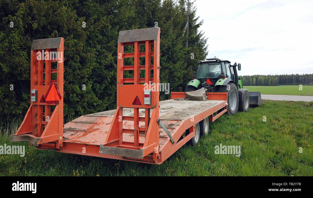 Traktor und Anhänger für die kompakten Hydraulikbagger auf Gras. Kopieren Sie Platz. Stockfoto